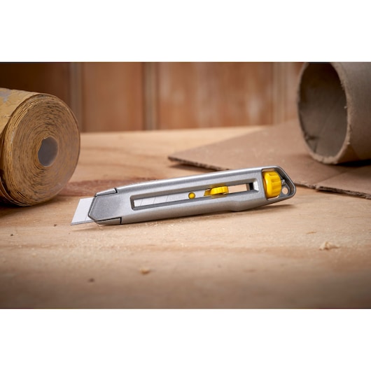 STANLEY 0-10-018 utility knife with silver body and yellow accents on a wooden surface, side view.