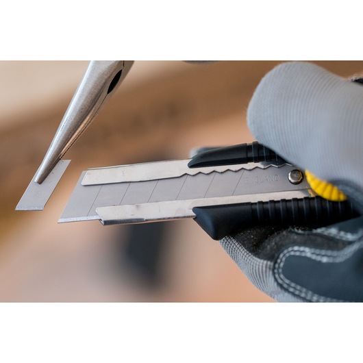 STANLEY 0-10-418 snap-off utility knife held by gloved hand, close-up of blade segment being removed.