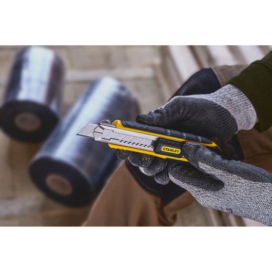 Photo of STANLEY 0-10-481 utility knife with segmented blade, held in a gloved hand, product in use.