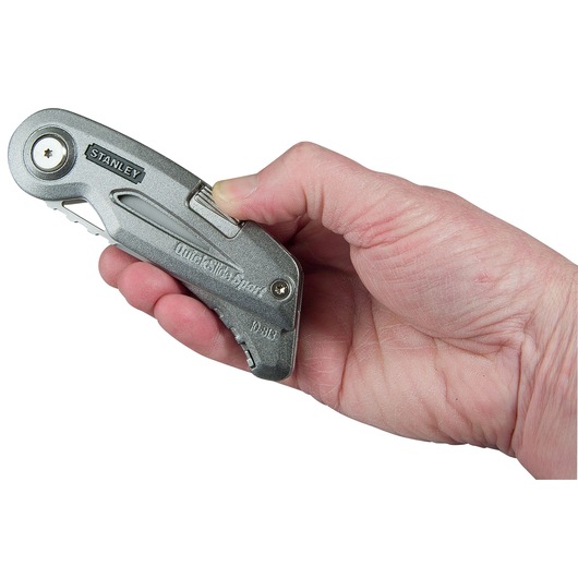 Photo of STANLEY 0-10-813 utility knife held in a hand, silver metal body, side view.