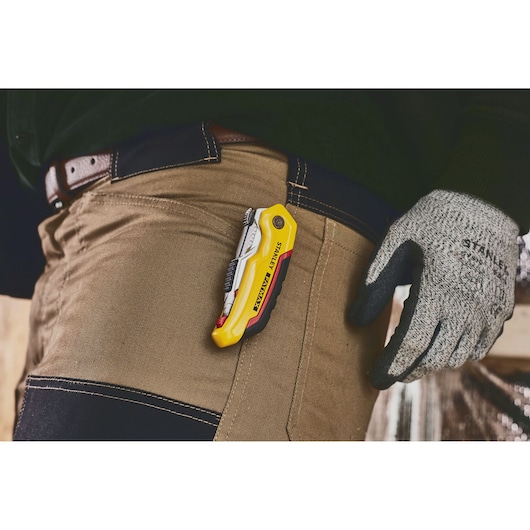 STANLEY 0-10-825 utility knife clipped to brown work pants, person wearing gloves.