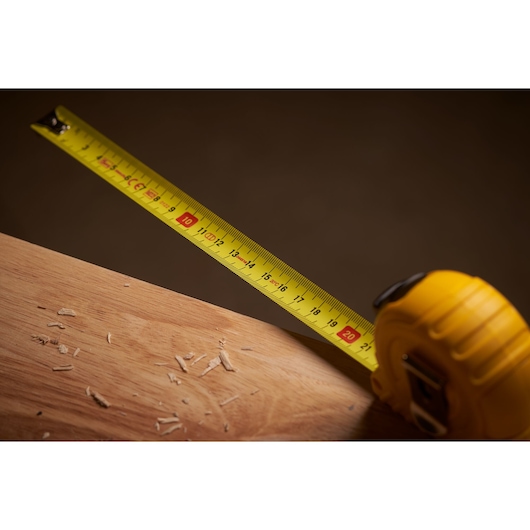 STANLEY 0-30-457 tape measure with yellow blade extended on wooden surface, close-up angle.