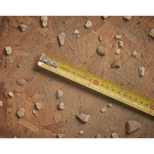 STANLEY 0-30-457 yellow tape measure on rough wood with scattered small rocks, top view.