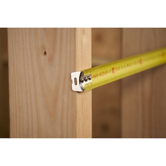 STANLEY 0-30-457 tape measure on wood, close-up angle, yellow blade with black and red markings.
