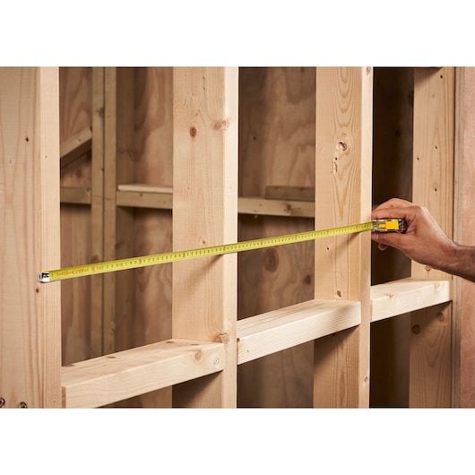 STANLEY 0-33-218 tape measure stretched across wooden framing, photo of product in use.