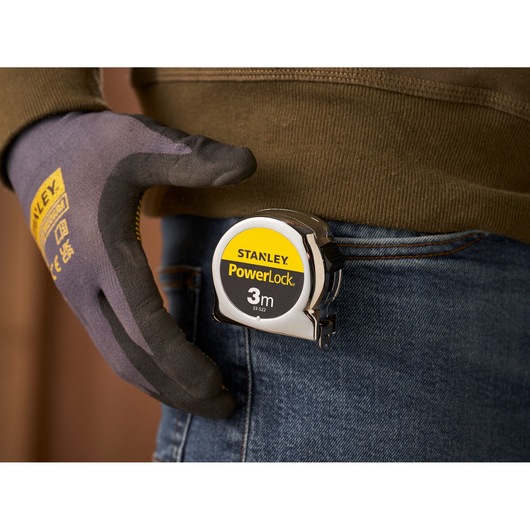 Photo of STANLEY 0-33-522 PowerLock 3m tape measure clipped to jeans pocket, person wearing work glove.