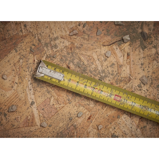 STANLEY 0-33-527 tape measure on plywood surface with scattered small rocks.