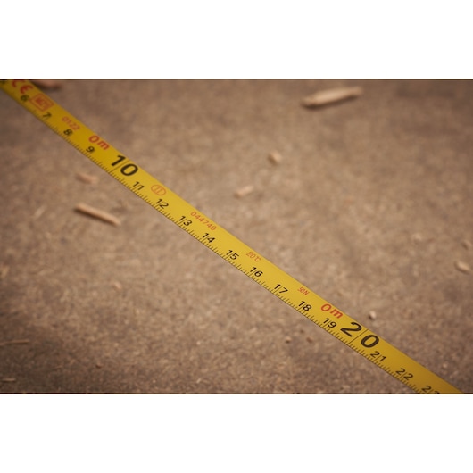 STANLEY 0-34-105 yellow measuring tape laid out on a brown surface, close-up view, Photography.