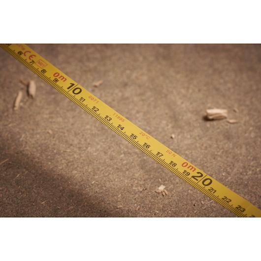 STANLEY 0-34-406 measuring tape close-up, showing yellow metric scale on sandy ground.