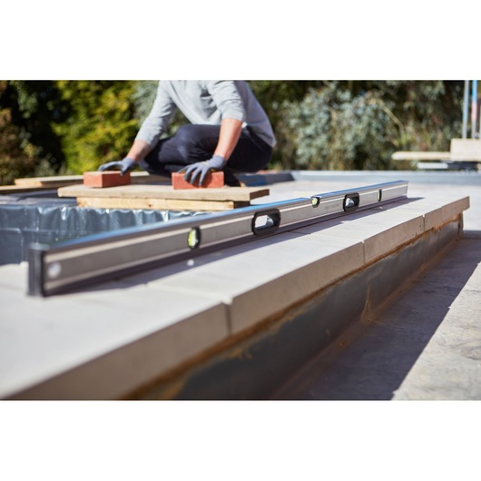 STANLEY 0-43-672 spirit level on construction site with worker using bricks outdoors.