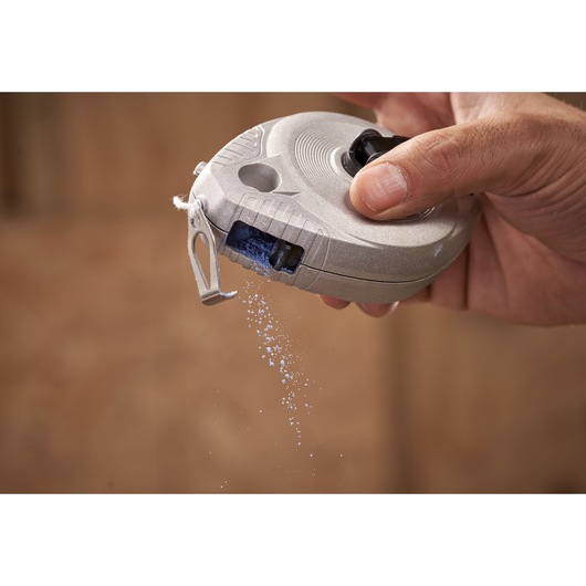 Photo of STANLEY 0-47-100 chalk line reel dispensing blue chalk powder, close-up in hand.