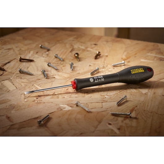 STANLEY 0-65-006 FATMAX slotted screwdriver on wood surface with scattered screws.