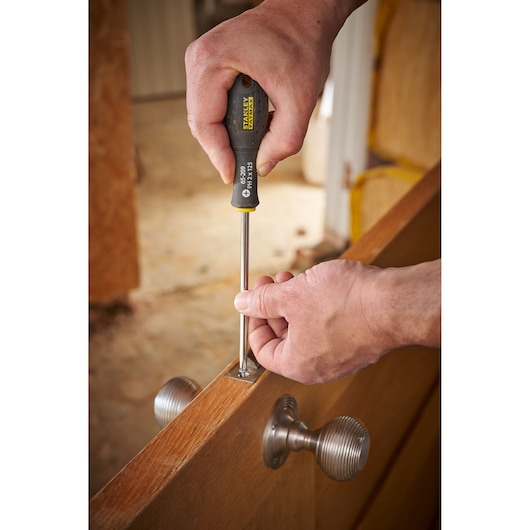 Photo of a person using a STANLEY 0-65-209 screwdriver to install a screw in a door hinge.