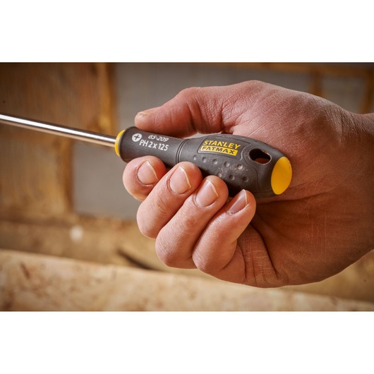 Photo of STANLEY 0-65-209 screwdriver with yellow and black FATMAX handle held in hand, close-up view.
