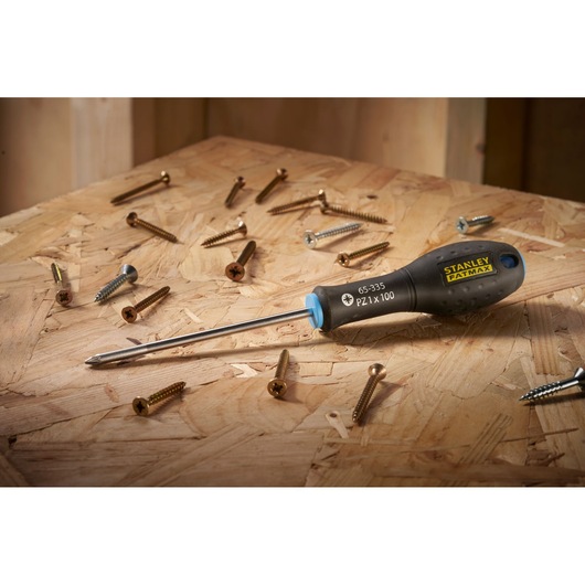 STANLEY 0-65-335 screwdriver with black handle on wooden surface surrounded by assorted screws.