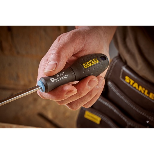Photo of STANLEY 0-65-337 screwdriver with black handle and yellow logo, held in hand, close-up view.