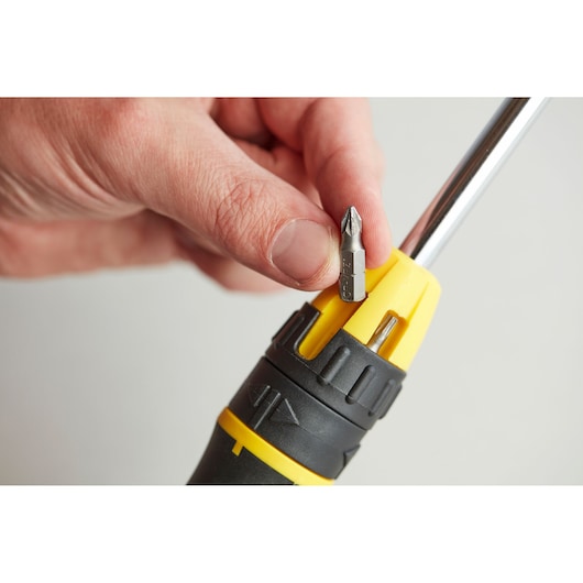 STANLEY 0-68-010 screwdriver handle with yellow and black grip and hand holding a screwdriver bit, close-up.