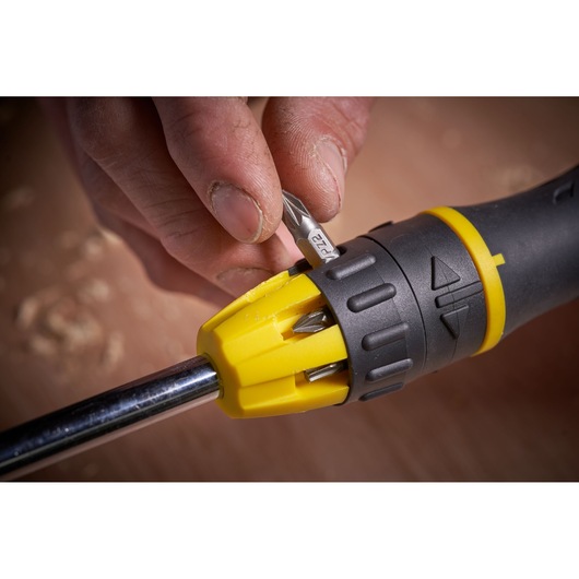 Stanley 0-68-010 screwdriver with yellow and black handle, close-up showing bit selection mechanism in use.