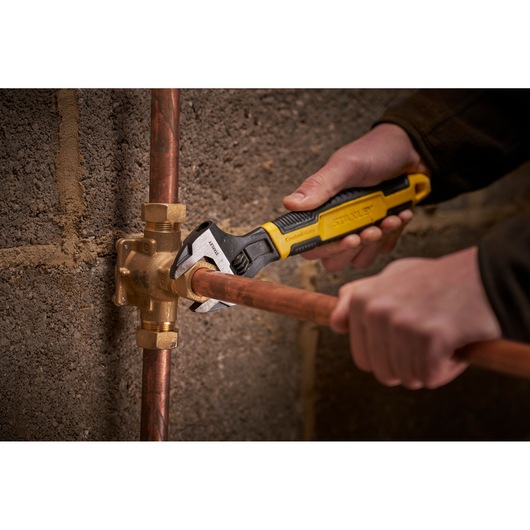 STANLEY 0-90-947 adjustable wrench used on copper pipe fitting, close-up indoor photography.