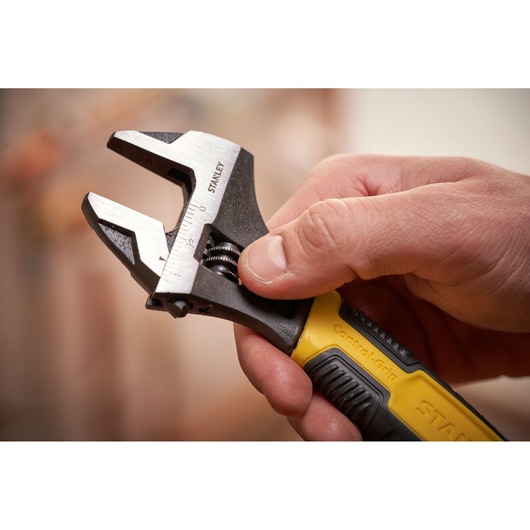 STANLEY 0-90-947 adjustable wrench with yellow and black handle held in hand, close-up photography.