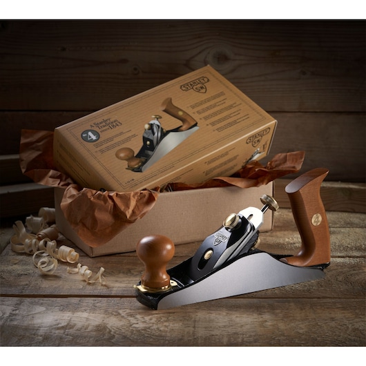 STANLEY 1-12-136 hand plane with wooden handles on rustic table, product box in background.