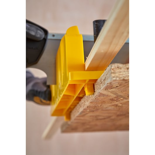STANLEY 1-20-600 photography of yellow miter box with saw cutting wood from top angle.