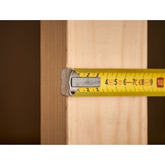 STANLEY 1-33-198 yellow tape measure measuring wooden beam, close-up photography.
