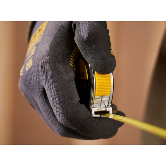 Photo of a gloved hand holding a STANLEY 1-33-238 tape measure, yellow and black, product in use.