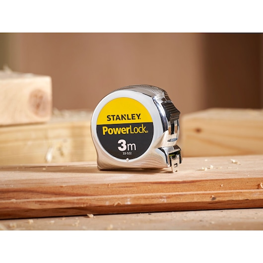 STANLEY 1-33-522 tape measure, PowerLock model, 3m, silver body, close-up photo on wooden surface.