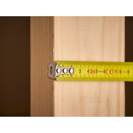 STANLEY 1-33-522 tape measure shown measuring wooden plank, close-up side angle.