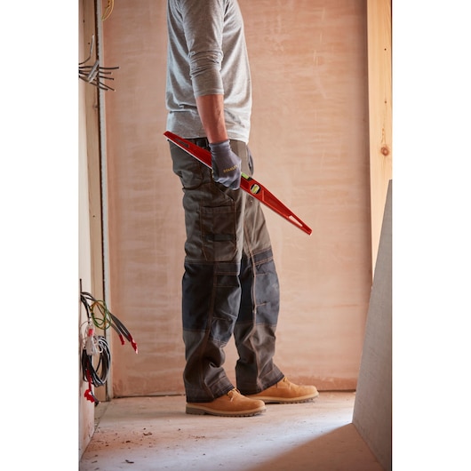 Photo of a person wearing work gloves holding a STANLEY 1-42-314 level tool at a construction site.