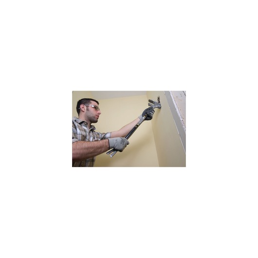 Photo of a person using a STANLEY 1-55-120 demolition bar to remove material from a wall indoors.