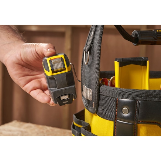 Photo of STANLEY 1-93-952 tool belt with hand holding a tape measure and tools inside yellow pockets.
