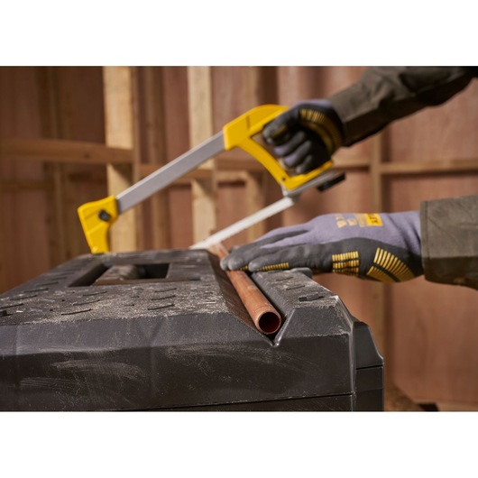STANLEY 1-95-612 photography of hands sawing copper pipe on black workbench in workshop.