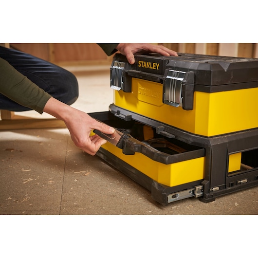 Stanley 1-95-829 tool box with drawer open, yellow and black, in workshop setting.
