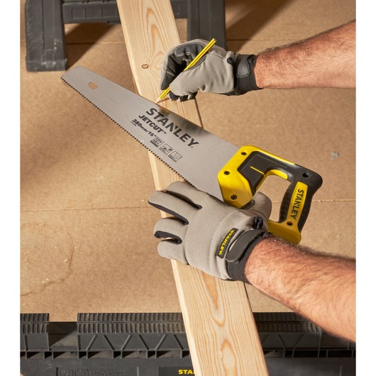STANLEY 2-15-594 hand saw with yellow handle held on wood plank, close-up angle.