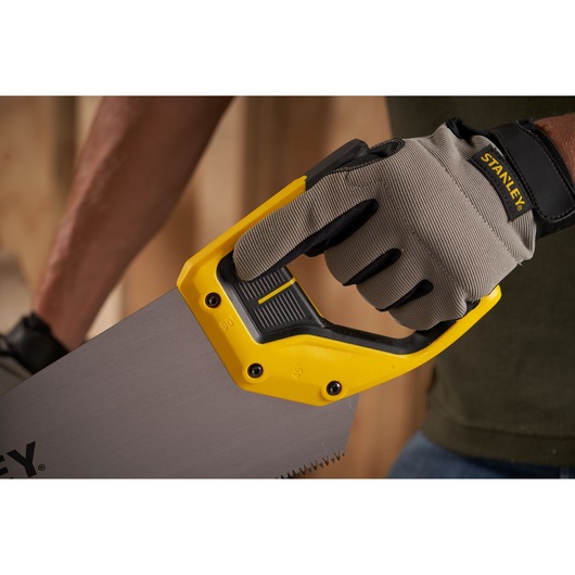 Photo of STANLEY 2-15-599 hand saw with yellow and black handle held by a gloved hand, product in use.