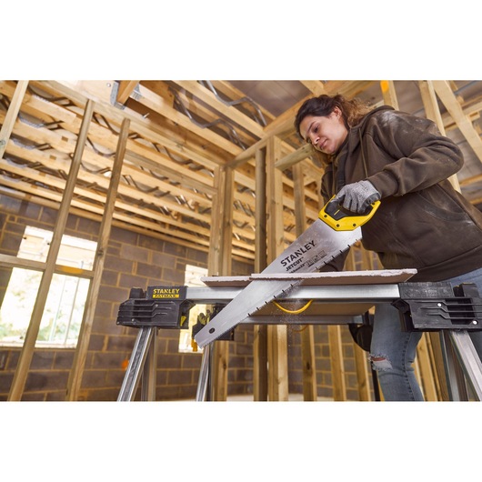 STANLEY 2-20-037 hand saw cutting wood, shown in action on STANLEY saw horses inside a framed construction site.
