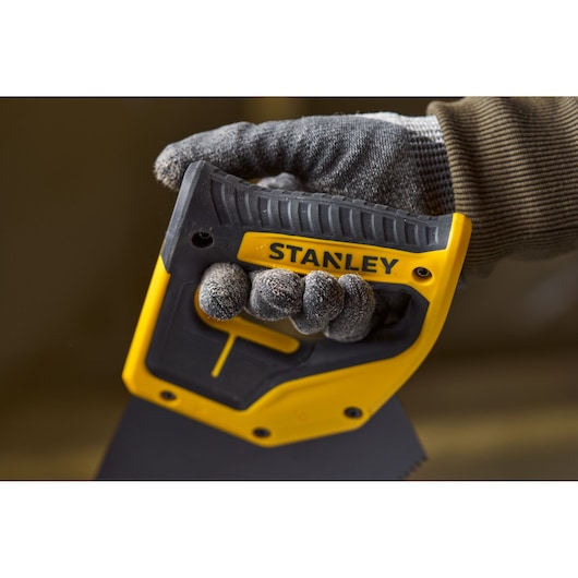 Photo of STANLEY 2-20-180 handsaw with yellow and black handle, held by gloved hand.
