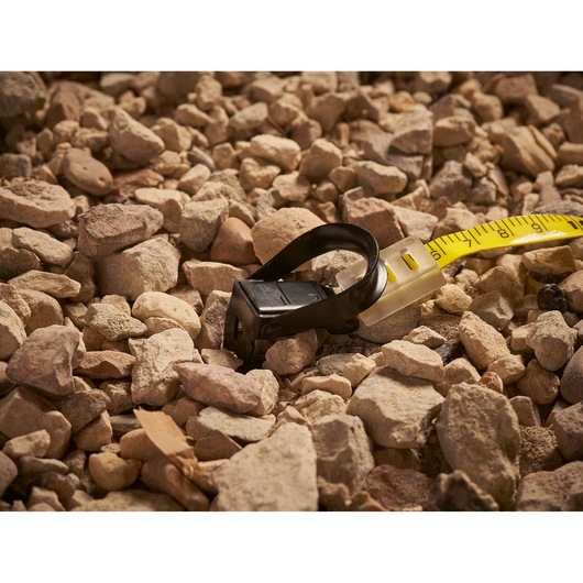 Stanley 2-34-777 measuring tape with black loop on rocky ground, close-up photography.