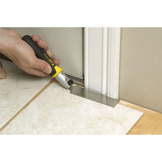 STANLEY 3-20-331 hand saw with black and yellow handle cutting door frame near floor, close-up view.