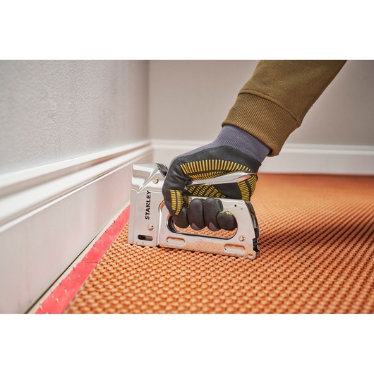 Photo of STANLEY 6-TR110 manual staple gun used to fasten carpet, close-up, side angle.