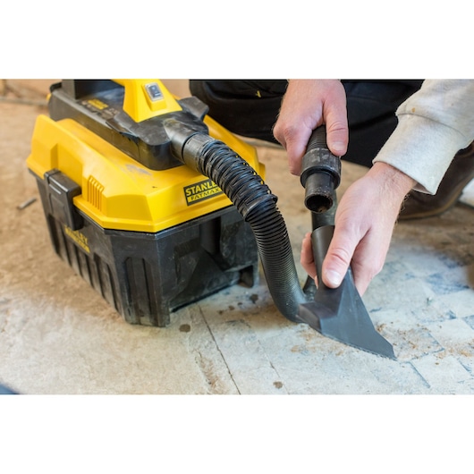 Photo of STANLEY FMC795B wet dry vacuum with yellow and black body, hose and nozzle on a work floor.