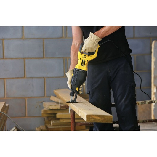 STANLEY FME365K reciprocating saw in use cutting wood plank, construction setting, product demonstration.