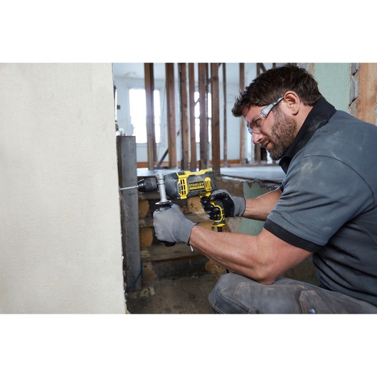 Photo of worker using STANLEY FMEH750K corded hammer drill to drill into concrete wall at construction site.