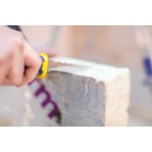 Photo of STANLEY FMHT0-10327 utility knife cutting insulation block, close-up view.