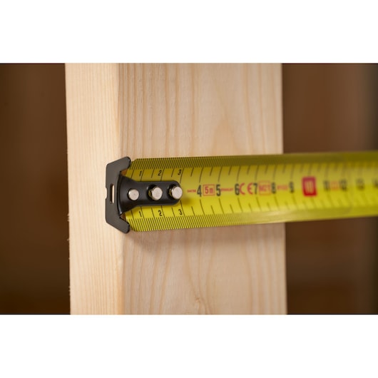 Stanley FMHT0-33864 tape measure in use measuring wood, close-up side angle.