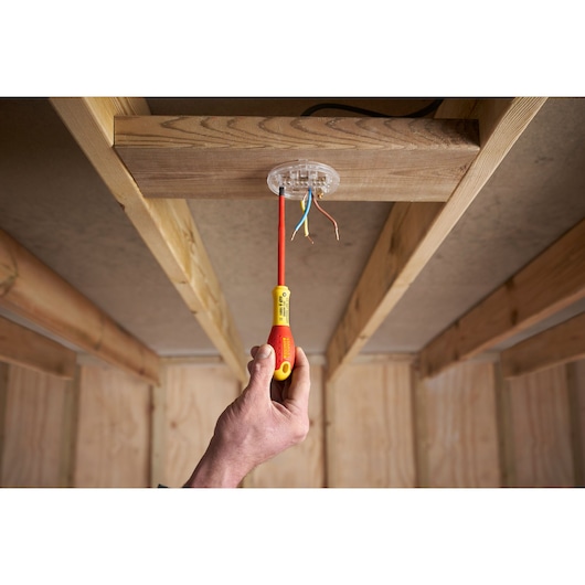 STANLEY FMHT0-62649 insulated screwdriver used on ceiling electrical junction, indoor wood frame.