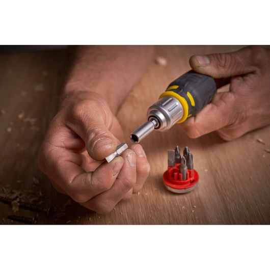 STANLEY FMHT0-62688 screwdriver set with interchangeable bits, close-up view of hands changing a bit on wooden surface.