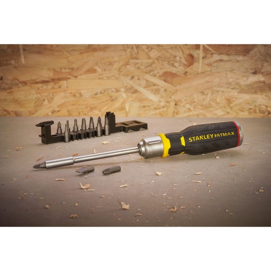 Stanley FMHT0-62690 screwdriver with interchangeable bits and holder on workshop surface, side angle.